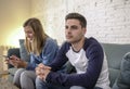 Young couple at home sofa couch with woman internet and mobile phone addiction ignoring her boyfriend feeling sad jealous frustrat Royalty Free Stock Photo