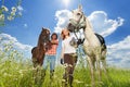 Young couple with horses walking in flowery meadow Royalty Free Stock Photo