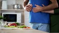 Young couple hugging during dinner preparation in kitchen, care and support