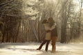 Young couple hugging and kissing in sunny snowy forest, background of icy trees, winter love. Romantic photo against sun Royalty Free Stock Photo