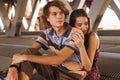 Young couple hugging in the summer daylight on a bridge construction in the city outdoors. copy space