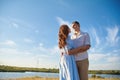 A young couple hugs in a field against the background of a river or lake and enjoy life. The concept of love and correct non- Royalty Free Stock Photo