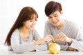 young Couple Inserting Coin In Piggybank