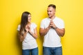 Young couple with insidious and grinning faces smile and something conceived dishonest isolated on yellow background. The concept