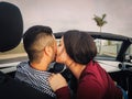 Young couple kiss in a convertible car during their road trip - Happy romantic newlywed date driving a cabriolet auto in honeymoon Royalty Free Stock Photo