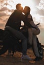 Young couple kisses next to a motorcycle