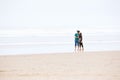 Young couple kissing on beach by ocean on foggy day