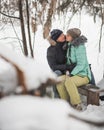 Young couple kissing on the bench in winter forest Royalty Free Stock Photo