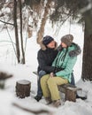 Young couple kissing on the bench in winter forest Royalty Free Stock Photo