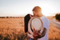Young couple kissing and hiding with a hat in a yellow field at sunset. Love and Summer time Royalty Free Stock Photo