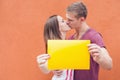 Young couple kissing and holding frame at background of wall Royalty Free Stock Photo