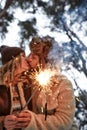 young couple kissing and holding sparklers on a background of snow-covered park and trees, loving couple, smiles on Royalty Free Stock Photo