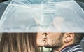 Young couple kissing under umbrella in a rainy winter day - Millennials lover having tender moments outdoor - Love, trends, fall,