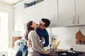 Young couple in the kitchen hugging and eating cheese.