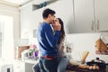 Young couple in the kitchen hugging and eating cheese.