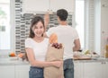 Young couple in the kitchen , woman with a bag of groceries shopping. Royalty Free Stock Photo