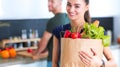 Young couple in the kitchen , woman with a bag of groceries shopping Royalty Free Stock Photo