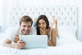 Young couple with laptop in the bed in room. Royalty Free Stock Photo