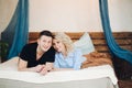 Young couple laying together on belly in white bed.