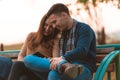 Young couple listening to music, smiling and looking at the phone and sitting on a bench in park Royalty Free Stock Photo