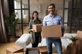 Young couple looking at camera holding packages in new home Royalty Free Stock Photo