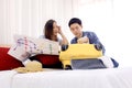 Young couple looking at the directions by phone and map while sitting together on bed at hotel room. Royalty Free Stock Photo