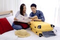 Young couple looking at the directions by tablet and map while sitting together on bed at hotel room. Couple of tourists searching Royalty Free Stock Photo