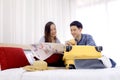 Young couple looking at the directions by tablet and map while sitting together on bed at hotel room. Couple of tourists searching Royalty Free Stock Photo