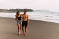 Young couple looking at each other while walking hand in hand together along a sandy beach. Royalty Free Stock Photo