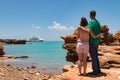 Young couple looking at modern cruise ship tied up to jetty surrounded by a turquoise sea at Broome in Western Australia framed by