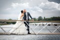 Young couple in love the bride and groom with a bouquet posing on a background pier with yachts