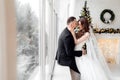 Young couple in love bride and groom posing in studio on background decorated with Christmas tree in their wedding day at