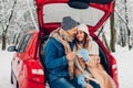 Young couple in love burning sparklers in car trunk in snowy winter forest. People relaxing outdoors during road trip Royalty Free Stock Photo