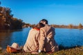 Young couple in love chilling by autumn lake. Happy man and woman enjoying nature and hugging Royalty Free Stock Photo