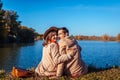 Young couple in love chilling by autumn lake. Happy man and woman enjoying nature and hugging Royalty Free Stock Photo