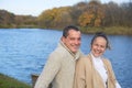 Young couple in love chilling by autumn lake. Happy man and woman enjoying nature and hugging Royalty Free Stock Photo