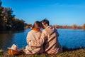 Young couple in love chilling by autumn lake. Happy man and woman enjoying nature and hugging Royalty Free Stock Photo