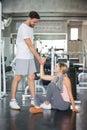 young couple in love exercise together in fitness gym . sport man boyfriend helping girlfriend to stand up or get up from floor. Royalty Free Stock Photo