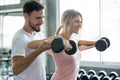 young couple in love exercising weight lifting dumbbells together in fitness gym . sport man boyfriend help girlfriend workout . Royalty Free Stock Photo