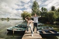 Young couple in love having fun with oars on the wooden bridge. stylish woman and man enjoy canoeing on sunny lake Royalty Free Stock Photo