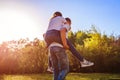 Young couple in love having fun in spring forest. Man rides his girlfriend on back at sunset. Royalty Free Stock Photo