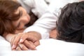 Young couple in love holding hands and looking at each other lying together on white bed Romantic moment Royalty Free Stock Photo