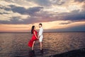 Young couple in love holding hands in the sea against the backdrop of a beautiful sunset. Royalty Free Stock Photo