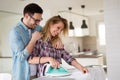 Young couple at home doing hosehold chores and ironing Royalty Free Stock Photo