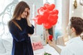 Young couple in love at home. Smiling man holding red box with marriage engagement ring got up on his knee and make proposal to