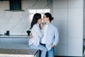 Attractive young woman and handsome man are enjoying spending time together while standing on light modern kitchen with cup of Royalty Free Stock Photo