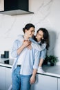 Attractive young woman and handsome man are enjoying spending time together while standing on light modern kitchen with cup of Royalty Free Stock Photo