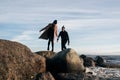 Young couple in love jumping over stones in water. Happy lovers have fun on the beach. Royalty Free Stock Photo