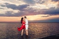 Young couple in love kisses standing in the sea against the backdrop of a beautiful sunset. Royalty Free Stock Photo