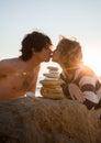 Young couple in love kissing on the ocean. in front of them is a balancing tower of stones